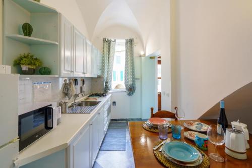 una cucina con mobili bianchi e un tavolo di legno di La casetta delle barche a Riomaggiore