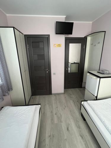 a room with two beds and a tv on the wall at Guest House MAX in Khmelʼnytsʼkyy