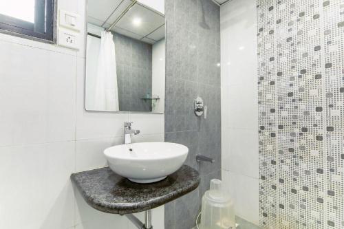 a white bathroom with a sink and a mirror at Magnus Square Business Hotel in Pune