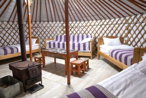 Una habitación con 2 camas y una estufa en una yurta en Dalain chimeg Resort Khuvsgul Province, Mongolia, 
