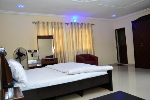 een slaapkamer met een bed met een stoel en een spiegel bij BBD Hotel And Suites in Ibadan