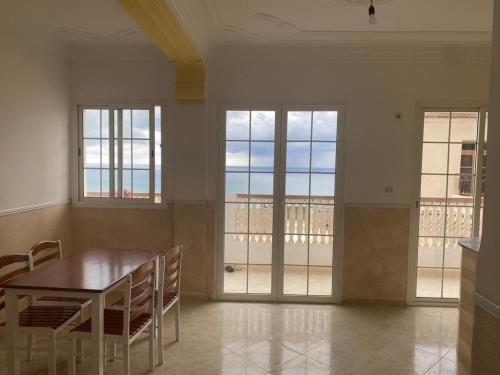 uma sala de jantar com mesa, cadeiras e janelas em BOUS Appartement Tichy 2 em Tichi