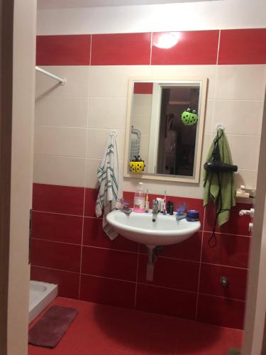 a red and white bathroom with a sink and a mirror at Cozzy hideaway in Durrës in Durrës
