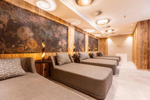 Zimmer mit 3 Betten und einer Wand mit Gemälden in der Unterkunft Zillertal Suites Fügen by ALPS RESORTS in Fügen