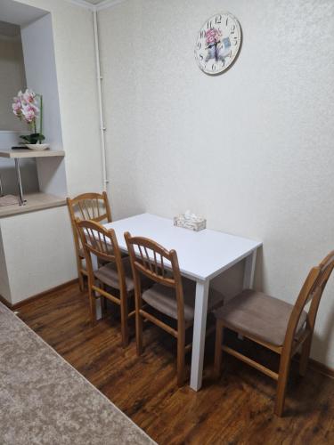 uma mesa com quatro cadeiras e um relógio na parede em Апартаменты в тихом месте em Chisinau