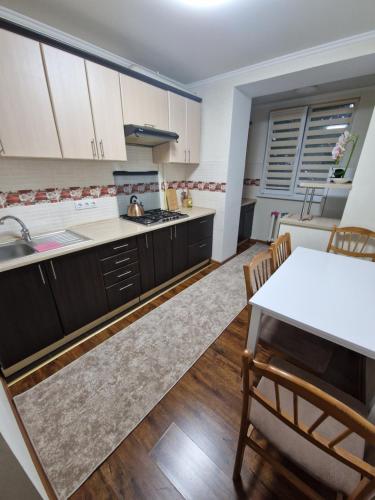 a kitchen with white cabinets and a table and chairs at Апартаменты в тихом месте in Chişinău