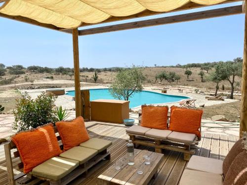 a patio with a table and chairs and a pool at Mama Adama - Alpaca Farm & Hotel in Grândola