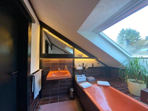 uma casa de banho com uma banheira laranja e um lavatório. em FeWo Skywalk Willingen em Stryck