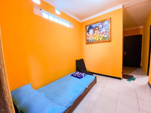 a bedroom with a blue bed in a yellow wall at Villa Satita in Batu