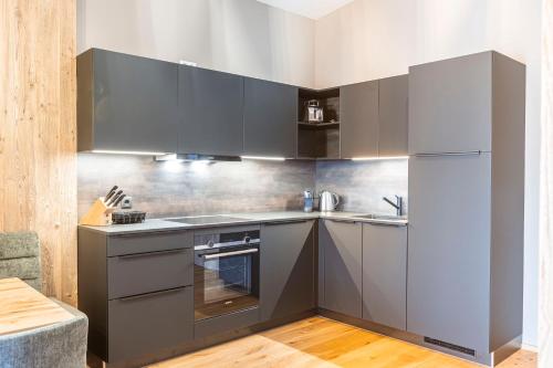 a kitchen with gray cabinets and a refrigerator at Zillertal Suites Fügen by ALPS RESORTS in Fügen