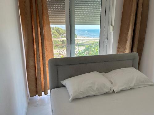 a bed with two pillows in front of a window at Apartments Doda in Ulcinj