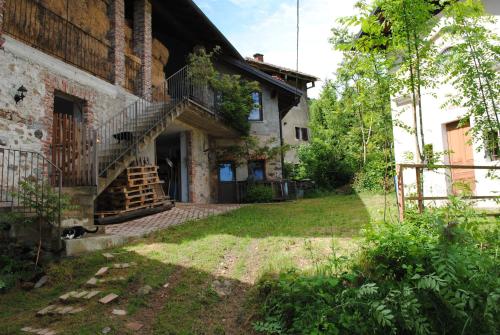 una vecchia casa con una scala nel cortile di Agriturismo I Sette Raggi ad Ailoche