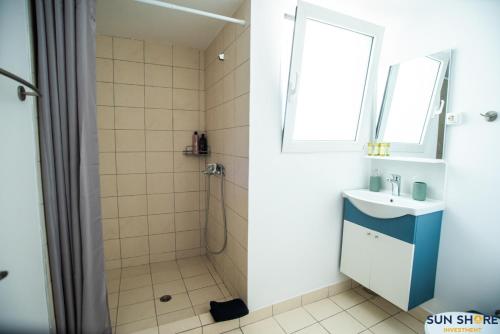 La salle de bains est pourvue d'une douche, d'un lavabo et d'une fenêtre. dans l'établissement Explore Greece from Comfortable City Centre Apartment, à Chalcis