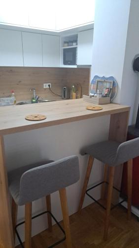 eine Küchentheke mit 2 Stühlen und einem Waschbecken in der Unterkunft LoRed apartment in Sarajevo