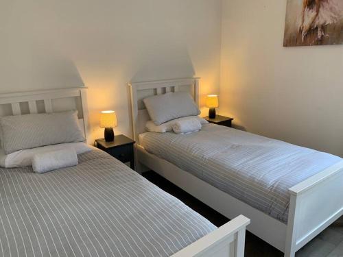 two beds in a room with two lamps on tables at Platform Church View Apartment Hull in Hedon