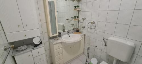 a white bathroom with a sink and a mirror at Apartment Riva Primošten in Primošten