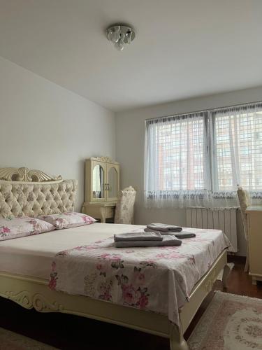a white bedroom with a large bed with pink sheets at Apartman Zvijezda, Zenica in Zenica