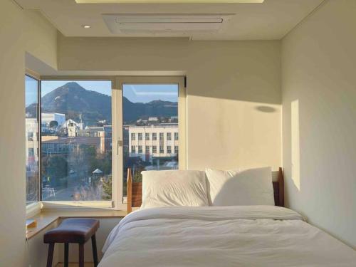 a bedroom with a bed and a large window at Exclusive Penthouse with Great Hanok Village View in Seoul