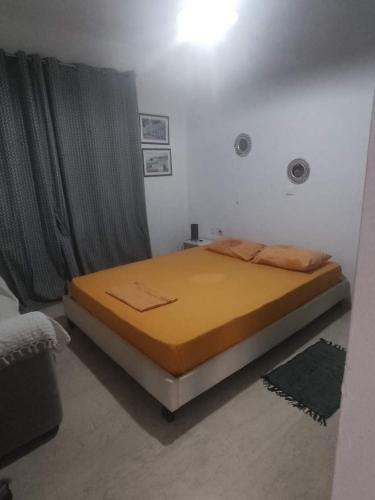 Bett in einem Zimmer mit gelber Tagesdecke in der Unterkunft Alex apartments relax in Agia Marina Mikrolimanou