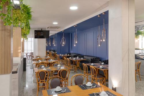 um restaurante com mesas e cadeiras de madeira e paredes azuis em Mogano Premium Hotel - ELETROPOSTO em Chapecó