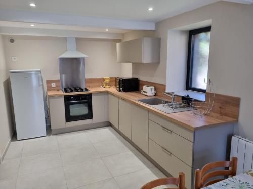 une cuisine avec un réfrigérateur blanc et un évier dans l'établissement Fontaine Vieille, à Saint-Georges-de-Luzençon