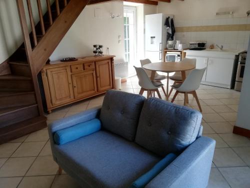 uma sala de estar com um sofá azul e uma mesa em La petite maison em Matha