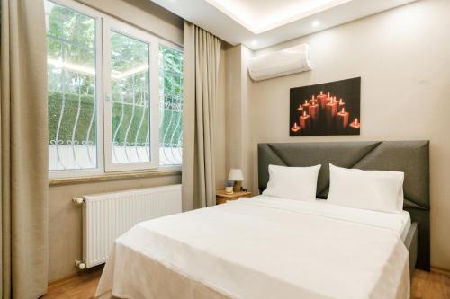 een slaapkamer met een groot wit bed en ramen bij Compact Flat 2 min to Metro, Near Marmara Park in Istanbul