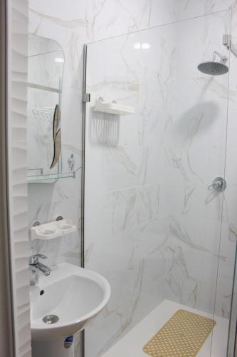 a white bathroom with a shower and a sink at Готель Гармонія. Термально-оздоровчий комплекс. in Uzhhorod