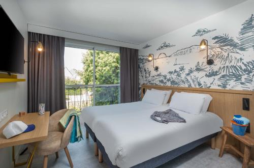a hotel room with a large bed and a window at L'Escale Marine, The Originals Relais in Crozon