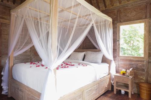 Un dormitorio con una cama con dosel y flores. en Nunu Bali Eco Friendly Retreat en Canggu