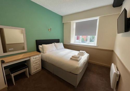 a bedroom with a bed and a desk and a mirror at Talbot Hotel in Stourbridge