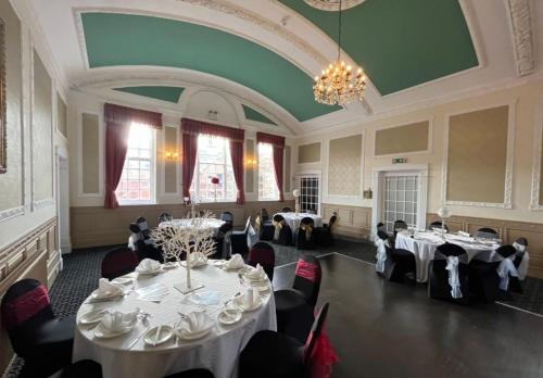 un salón de banquetes con mesas y sillas blancas y una lámpara de araña en Talbot Hotel en Stourbridge