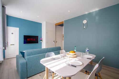 een eetkamer met een witte tafel en een blauwe bank bij Cocon d'Hiver - Netflix & Wifi - Parking Gratuit - check-in 24H24 - Kit Bébé Inclus - GoodMarning in Châlons-en-Champagne