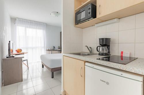 a kitchen with a sink and a microwave at Appart'City Classic Toulouse Tournefeuille in Tournefeuille