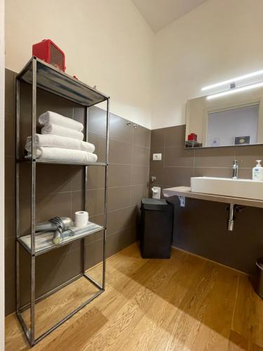 Sarah Apartment Verona Fiera في فيرونا: حمام مع حوض ورف مع المناشف