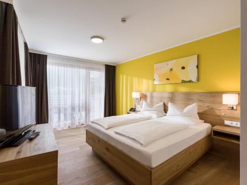 a bedroom with a large bed and a flat screen tv at DAS SIEBEN - Adults Only in Bad Häring