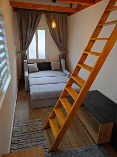 a living room with a ladder leading to a couch at The little White House in Sibiu