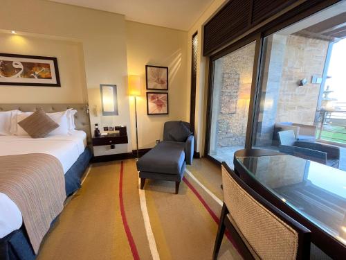 a hotel room with a bed and a chair and a window at Sofitel Al Khobar The Corniche in Al Khobar