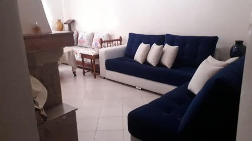 a living room with a blue couch and white pillows at Résidence riad Hay riad in Ifrane
