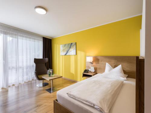 a bedroom with a bed and a yellow wall at DAS SIEBEN - Adults Only in Bad Häring