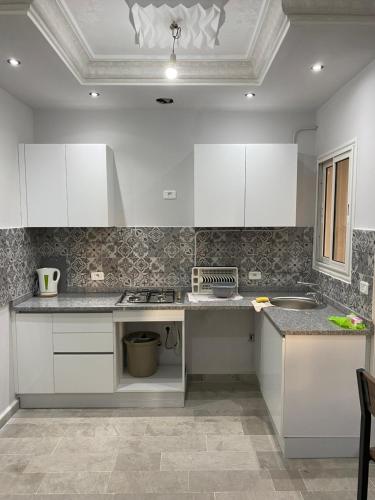 uma cozinha com armários brancos e bancadas em granito em Appartement meublé haut standing 2 chambres proche mer em Soliman