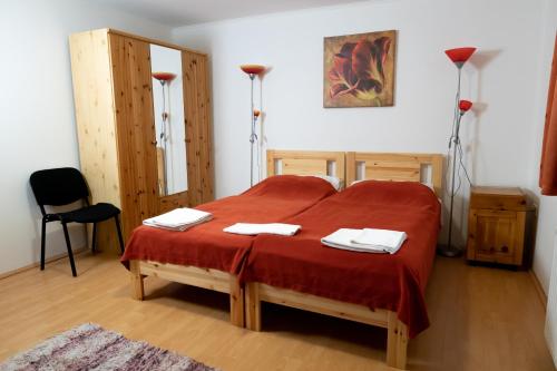 a bedroom with a large red bed with two towels at Liszt Apartman in Pécs