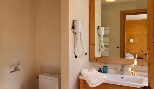 een badkamer met een wastafel, een spiegel en een telefoon bij Vacancéole - Résidence Cortina in Les Deux Alpes