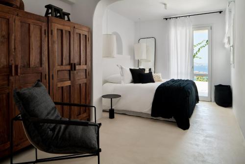 a bedroom with a bed and a chair and a window at Villa La Piscine Mykonos in Houlakia