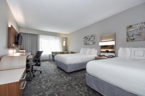 a hotel room with two beds and a desk at Courtyard by Marriott Charlotte Matthews in Matthews