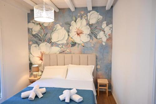 a bedroom with a bed with white flowers on the wall at Garofoli Apartments in San Giovanni Lupatoto