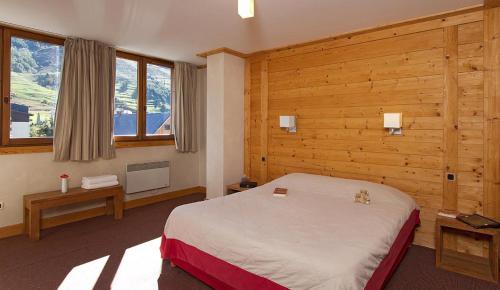 um quarto com uma cama e paredes e janelas de madeira em Vacancéole - Résidence Cortina em Les Deux Alpes