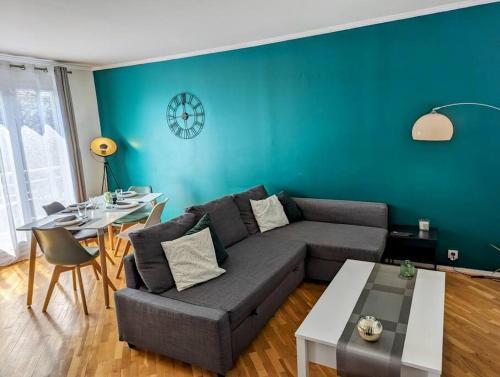 a living room with a couch and a table and a clock at Séjour en famille ou amis à Disneyland & Paris in Lognes