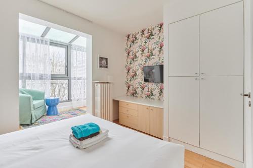 a white bedroom with a bed and a tv at Rent a Room apartments - Degas in Paris