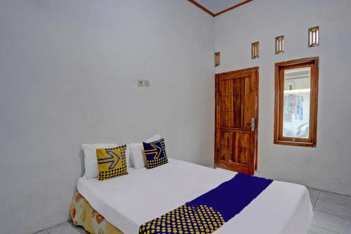 a bedroom with a white bed with yellow and blue pillows at SPOT ON 92906 Surya Indah Homestay Syariah in Mojokerto